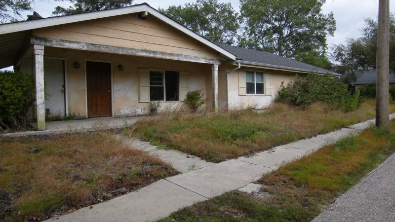 Older Austin house with peeling paint and an overgrown yard, sold as-is