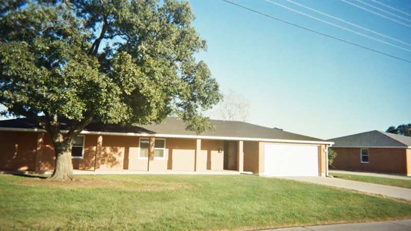 Single-story brick ranch house with a live oak tree in an Austin neighborhood
