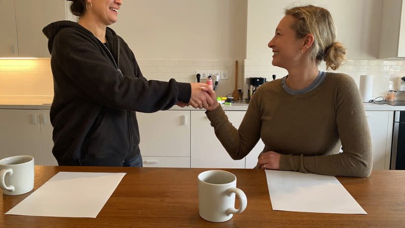 Homeowner and local home buyer shaking hands at a kitchen table